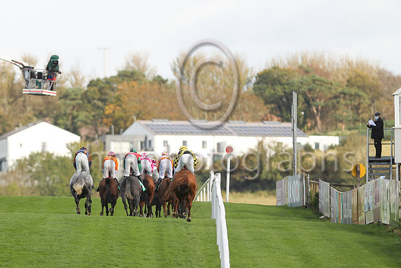 Horses and jockeys overseen by the TV Cameraman on the left and the Turf Club Steward on the right