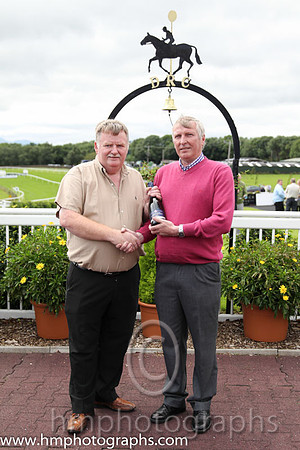 Race 1 - Ron McVeigh a member of staff at Downpatrick who had a birthday on the race day presenst champagne to the winning trainer Sean McParlan
