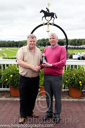 Race 1 - Ron McVeigh a member of staff at Downpatrick who had a birthday on the race day presenst champagne to the winning trainer Sean McParlan