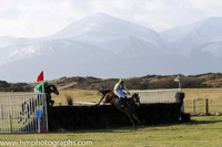 Horses jump fence 1 after the start of Race 1 at Tyrella with the snow covered Mourne Mountains as a backdrop